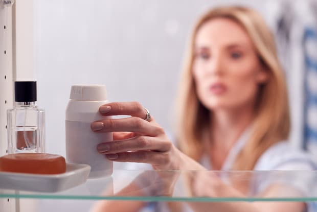 a woman reaching for medications in her cabinet