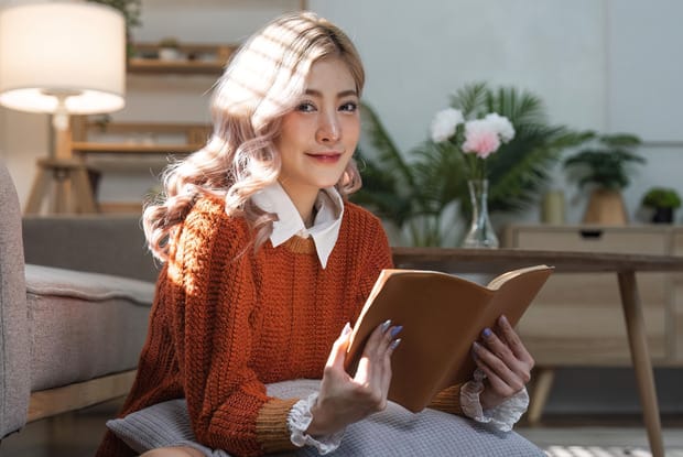 a woman leaning on a couch reading