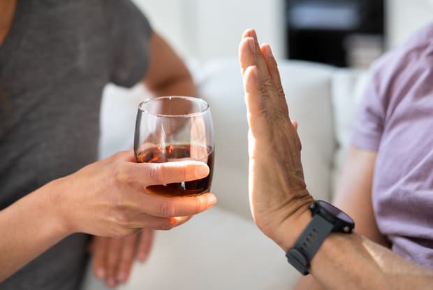 a man refusing a glass of alcohol