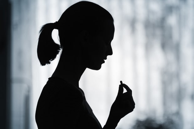 a silhouette of a woman taking a pill