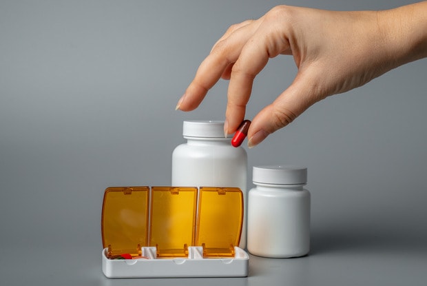 hand putting pill into pill container