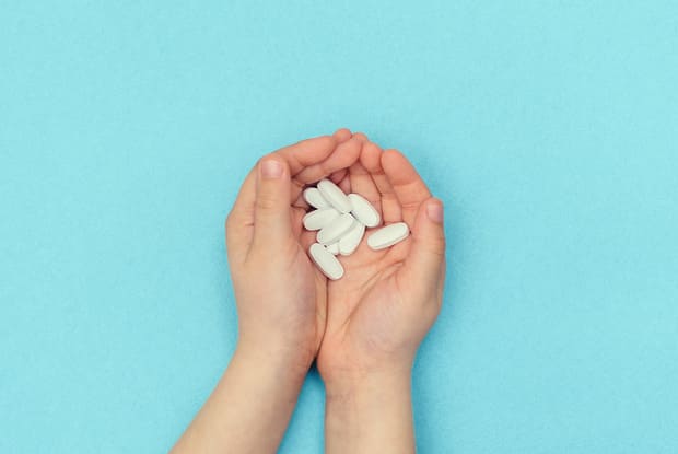 a person holding several pills in their palm