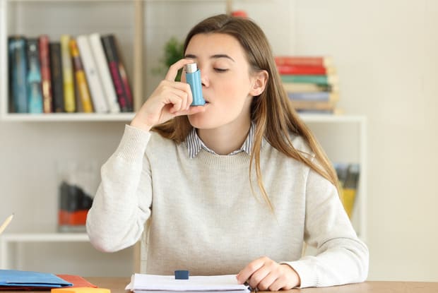 a woman using an asthma inhaler