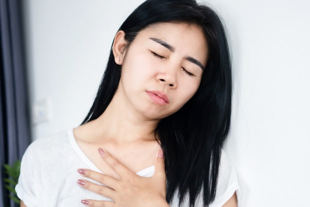 a woman holding her airways due to difficulty breathing