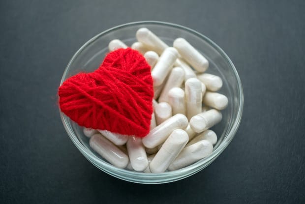 bowl of pills with heart of red yarn