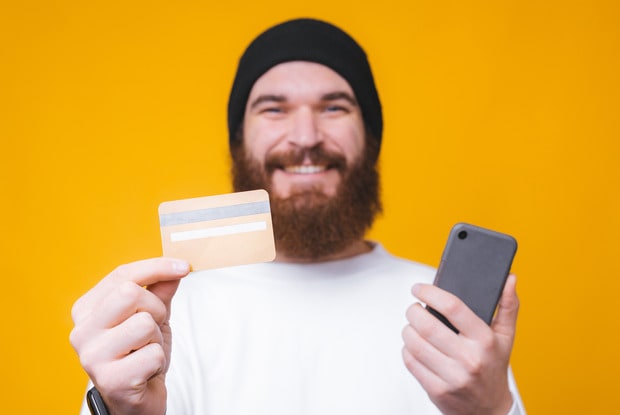 a man holding his credit card and phone