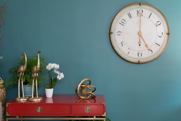 A red console table with gold accessories. The backgrounding wall is painted in The green hour (2018 colour of the year by Dunn Edwards).