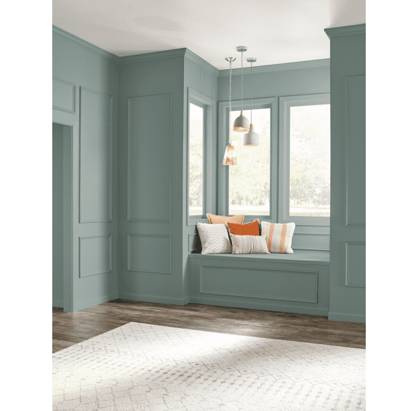 Window seat in a classic home. The walls are painted with In the Moment (2018 colour of the year by Behr). To complete the seating area, white suspension lights and cushions in the tones of white and orange.