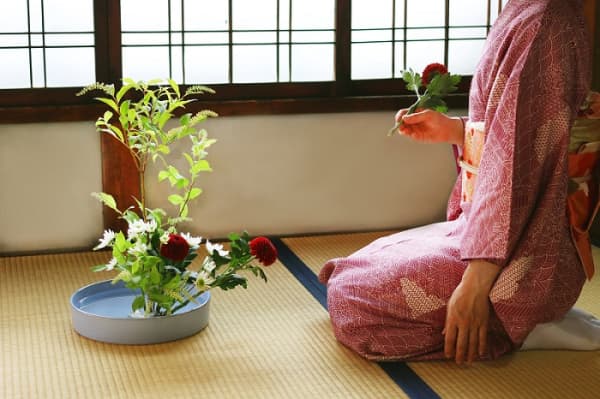 Woman arranging flowers in an Ikebana composition.