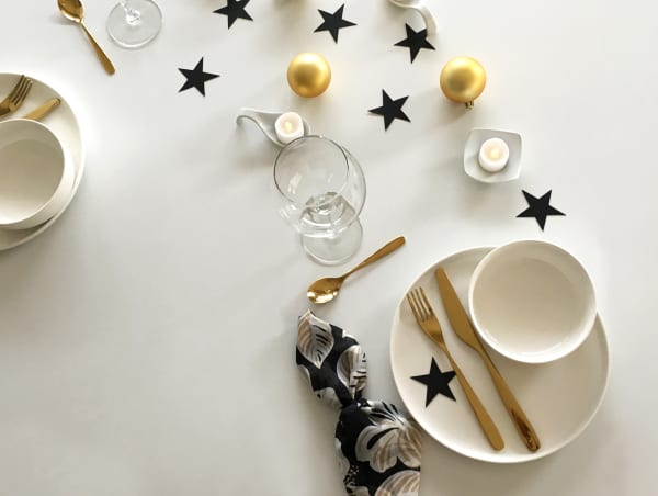 View of the same minimal modern Christmas table setting with two places arranged on consecutive sides of the table.
