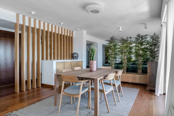 Tall plants visually dividing a dining room area.