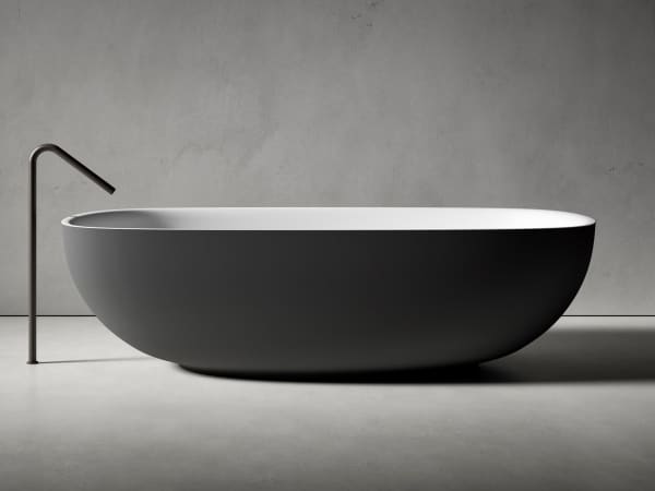 Bathtub with an oval shape and rounded floor-mounted faucet.