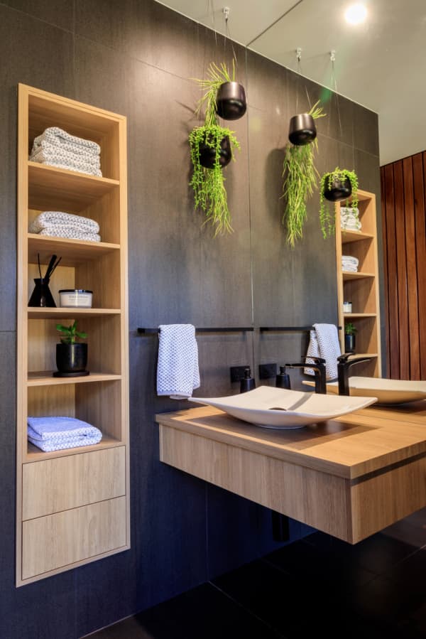 Plants hanging from the ceiling in a small bathroom.