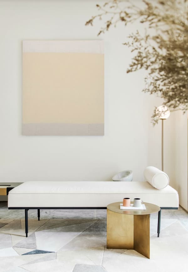 A minimal seating area: white daybed, gold side table and a minimal watercolor art in the background. Perfect setup to enjoy a silent moment.