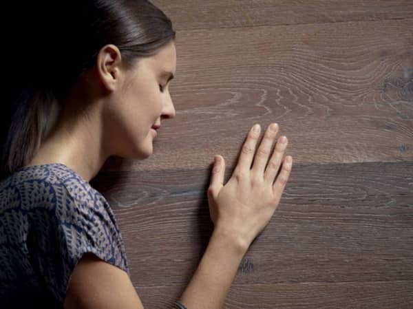 A woman touching a wooden surface.
