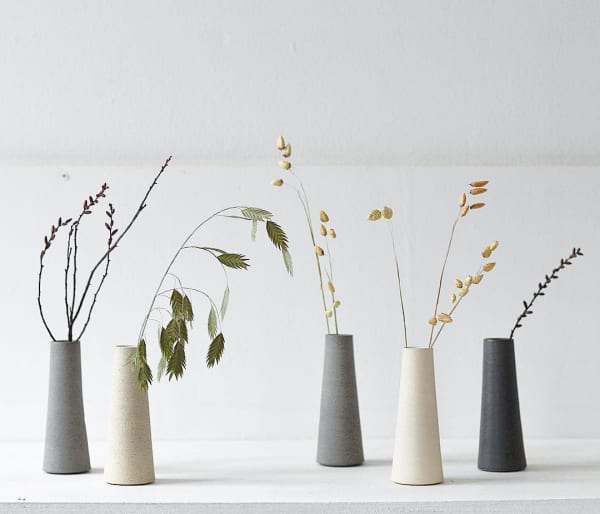 Minimal stone vases with various stems inside.