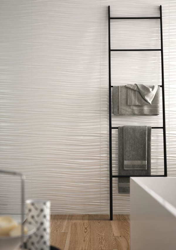 Bathroom wall with textured tiles recalling the wavy shape of sand moved by the wind.