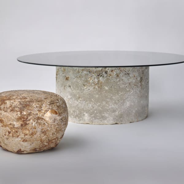 A round table with biofabricated base out of mycelium and glass top.