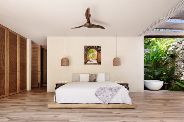 One of the bedrooms of Villa Verde. On the side of the bed is an opening to the outdoors, where a free-standing bathtub is located.