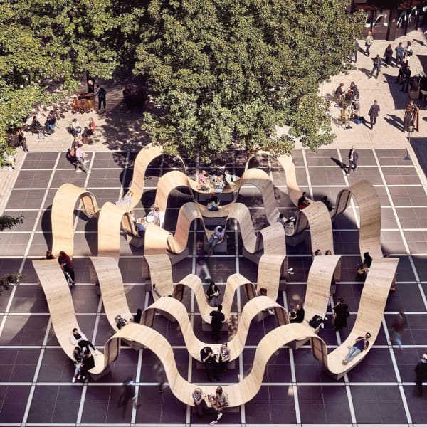 Bench with a curved profile that creates individual refuge areas for each person seating.