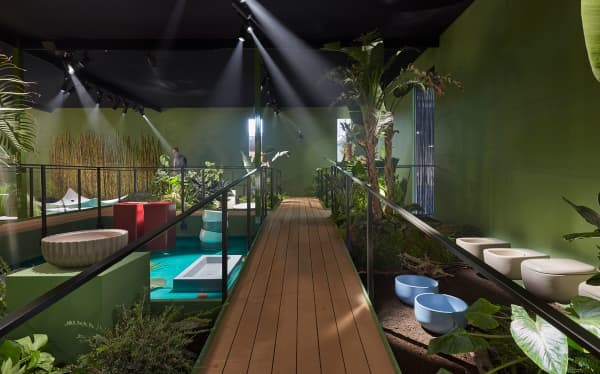 Booth designed as a walkway cutting through a jungle where toilets, sinks and bathtubs are displayed.