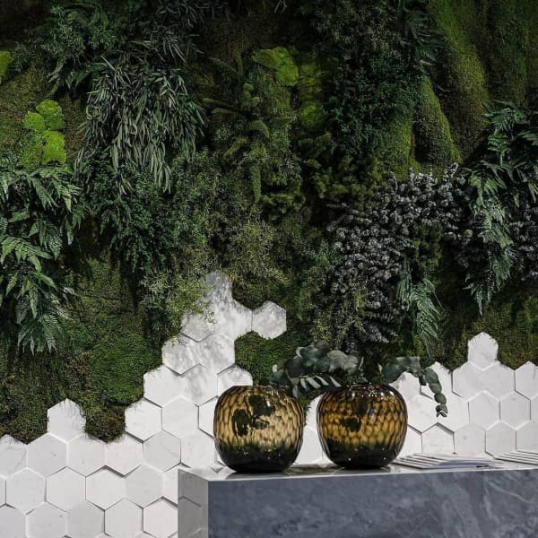Wall finished with hexagonal tiles on the bottom and a lush vertical garden on the top.