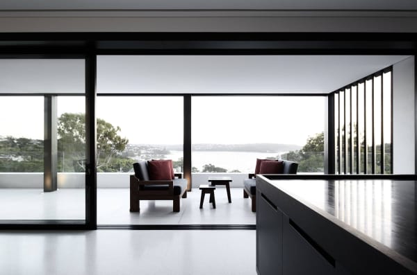 Interior opening on a balcony with a glazed balustrade that divides it from the deep vista over the sea.