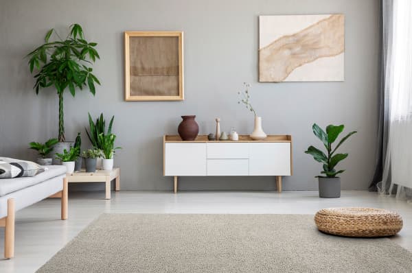 Living room decorated with earthy tones, plenty of plants and a beige modular rug on the floor.