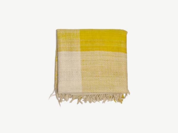 Blanket with yellow and beinge squares.