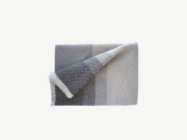 Grey blanket with a herringbone white pattern.