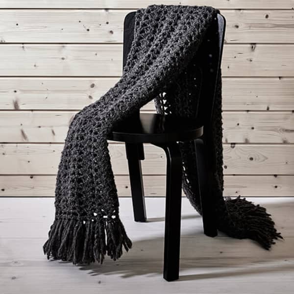 Dark grey crocheted blanket lying on a chair.