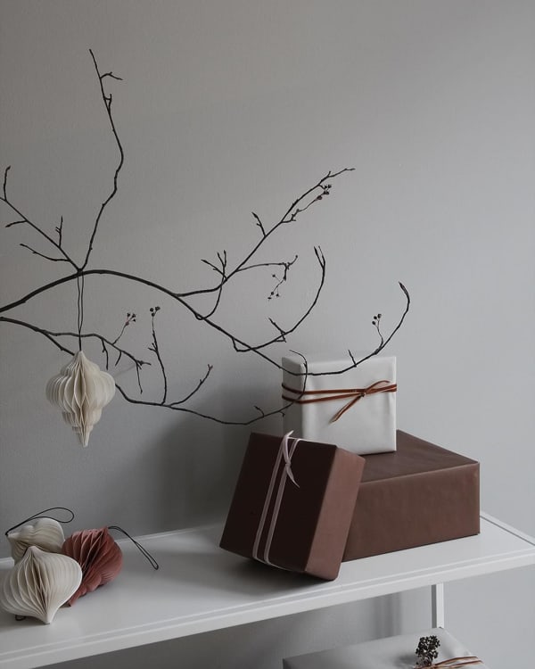 Branch decorated with paper ornaments in earthy tones.