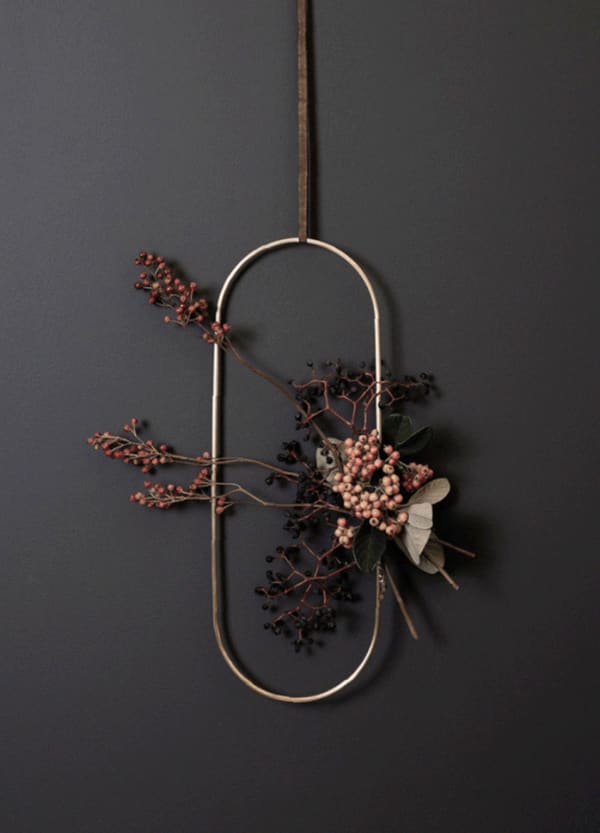 Oval metal wreath decorated with berry branches.