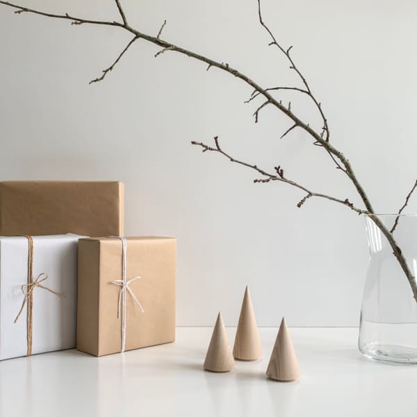 Wooden minimal trees on a table with gifts next to them.