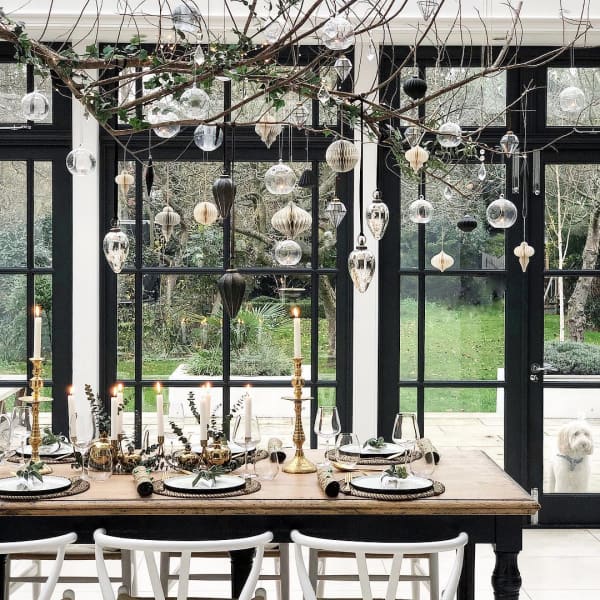 Branch with vintage ornaments hung over a modern dining table.