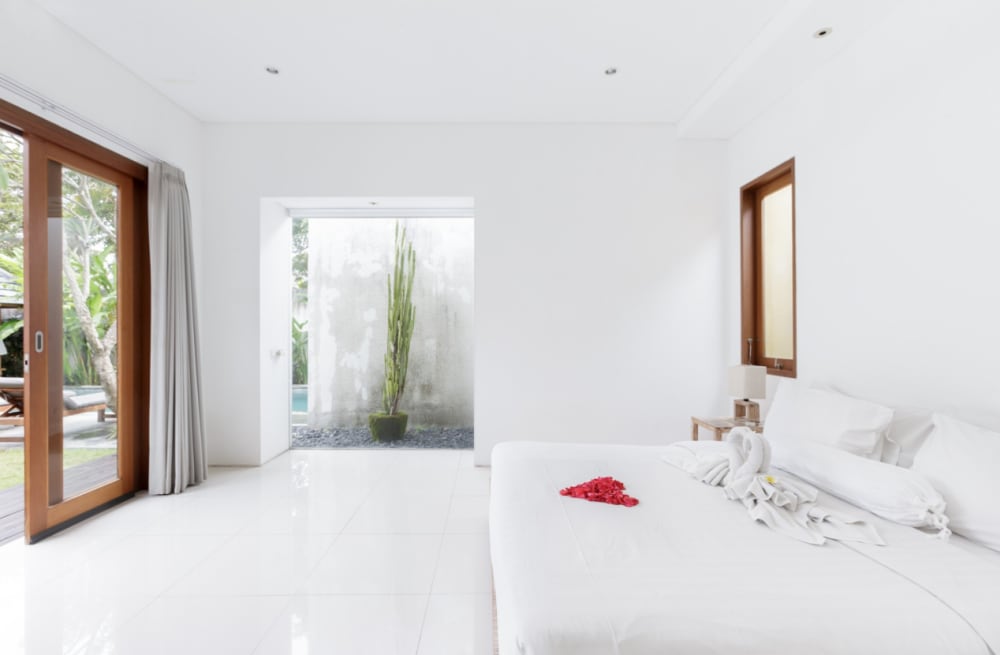 Bedroom with a glass part of the wall containing plants and opening the view to the outdoors.<span class="sr-only"> (opened in a new window/tab)</span>