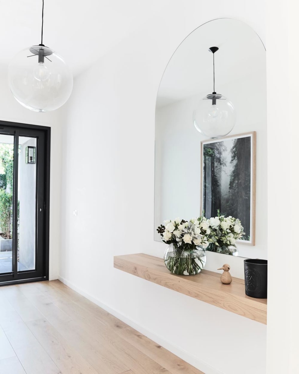 Contemporary entryway with a wood shelf popping against a white wall.<span class="sr-only"> (opened in a new window/tab)</span>