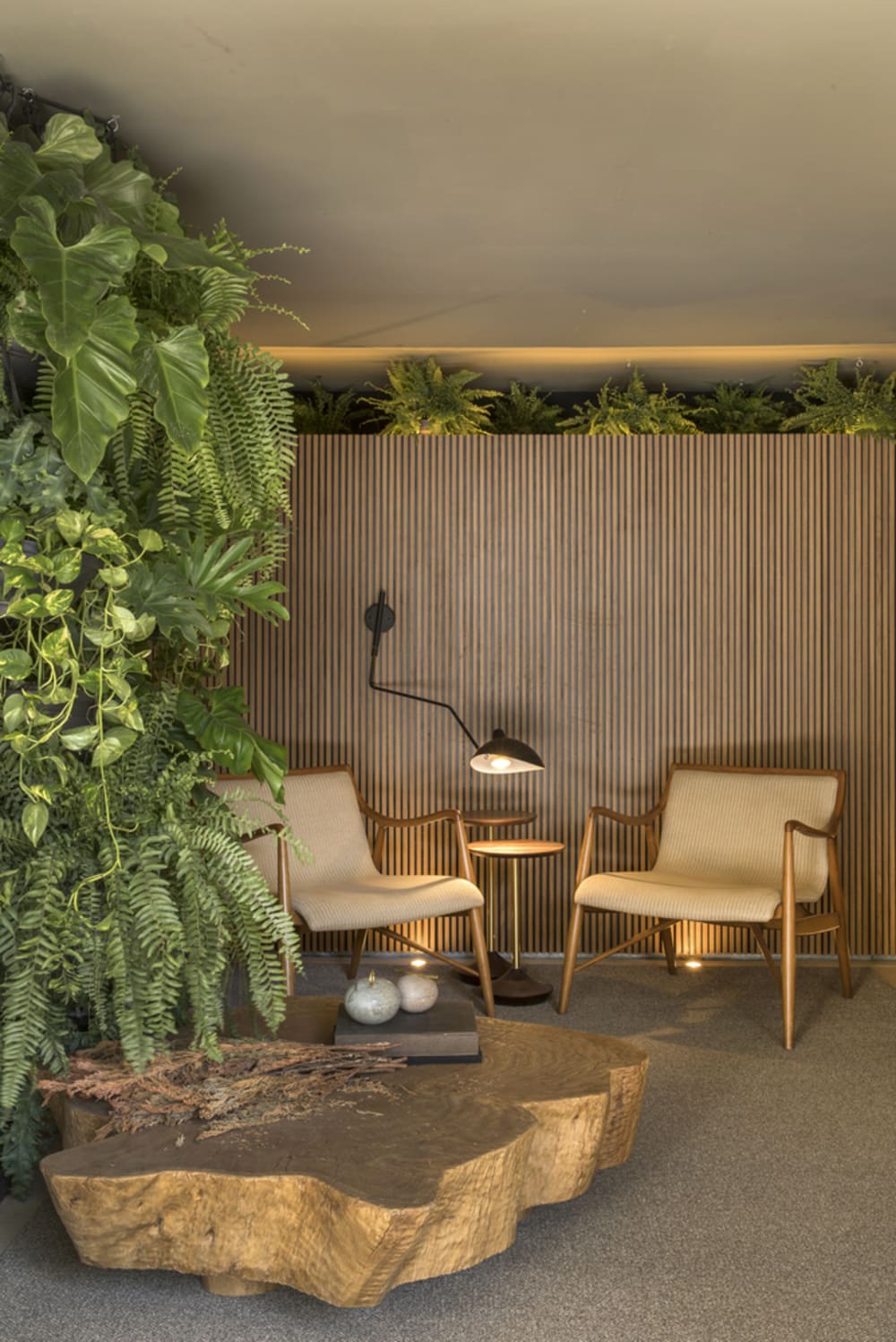A seating area in a room with a vertical garden on the side and more plants hanging from the ceiling.<span class="sr-only"> (opened in a new window/tab)</span>