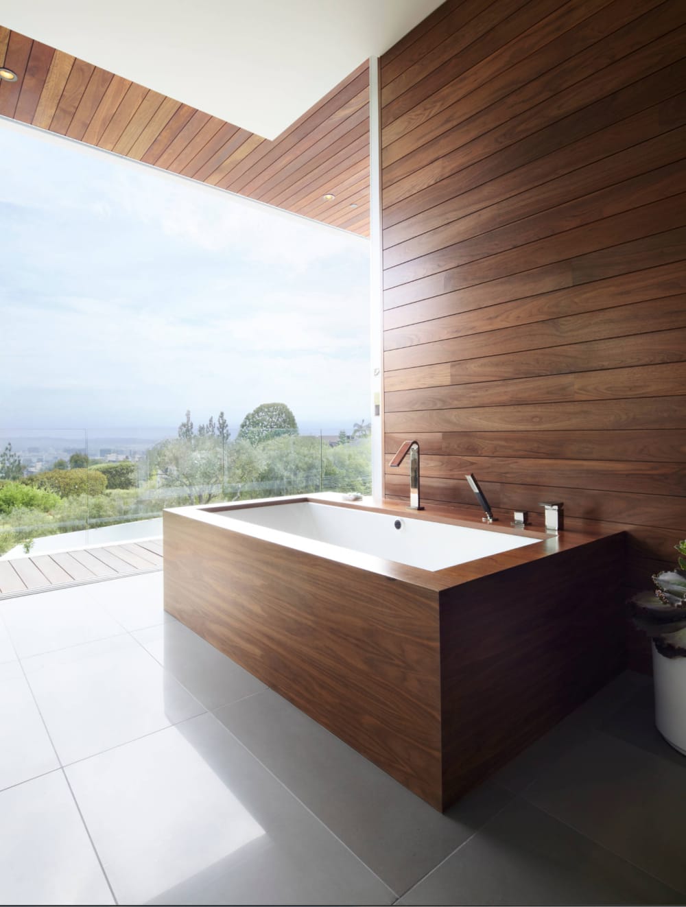 A contemporary bathroom with smooth wood panels on the wall as well as around the bathtub.<span class="sr-only"> (opened in a new window/tab)</span>