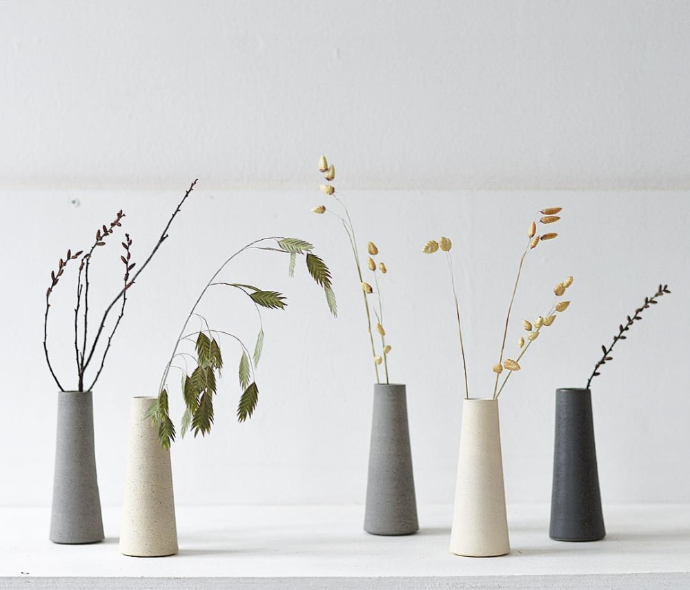 Minimal stone vases with various stems inside.<span class="sr-only"> (opened in a new window/tab)</span>