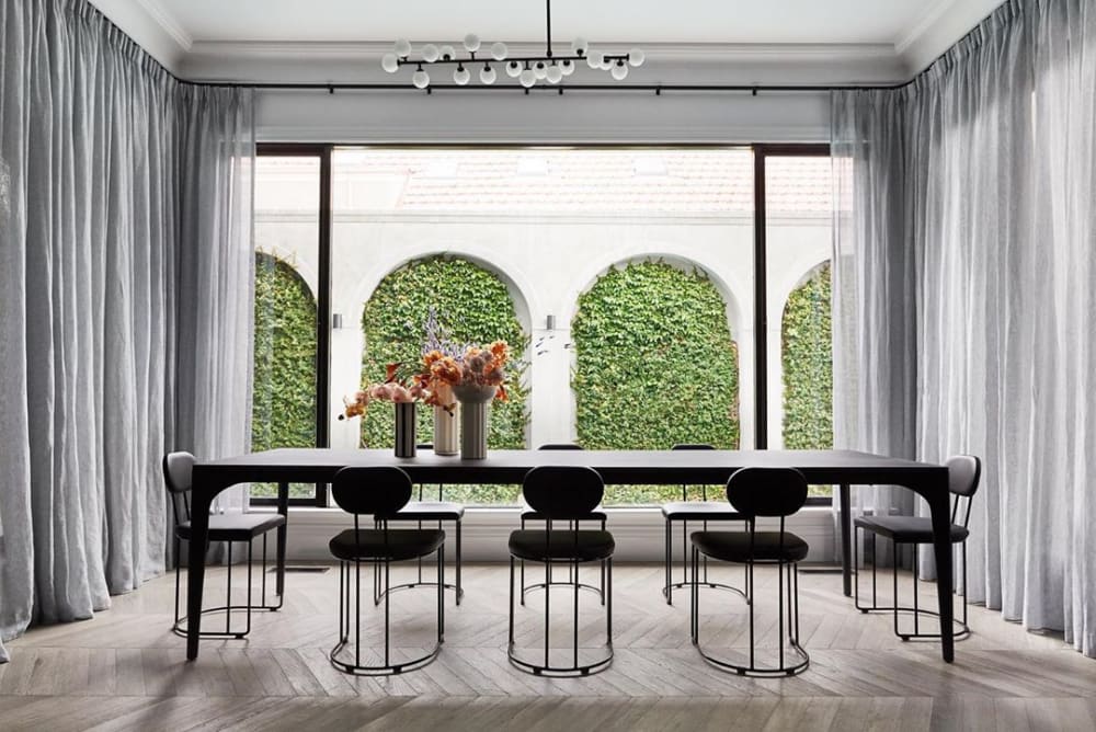 Dining room looking into a patio whose back wall is decorated with vertical greenery enclosed into arched niches.<span class="sr-only"> (opened in a new window/tab)</span>