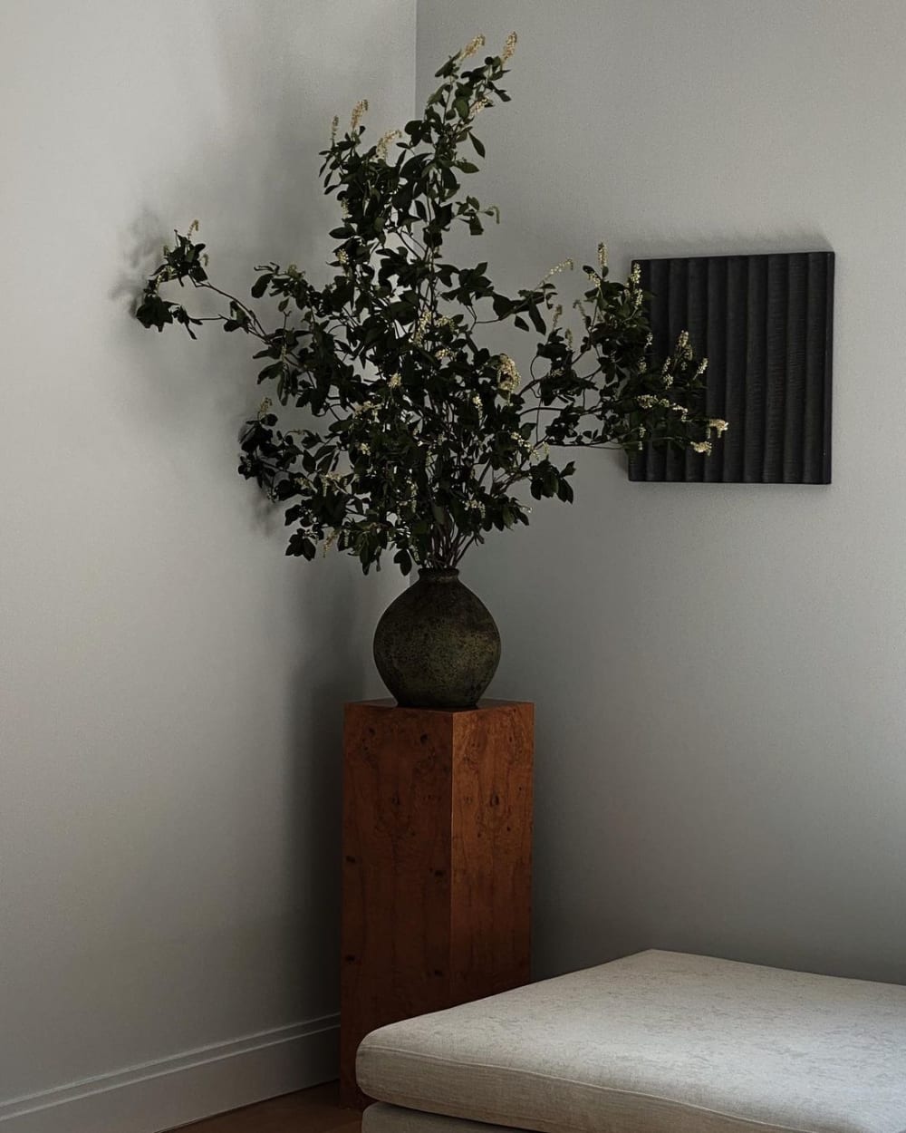 Oversized branch styled over a wooden stool in the corner of a room.<span class="sr-only"> (opened in a new window/tab)</span>