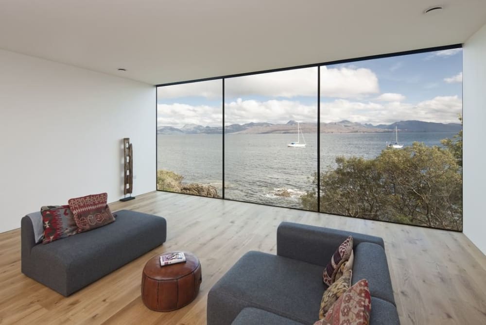Living room with a full-wall window looking into the sea.<span class="sr-only"> (opened in a new window/tab)</span>