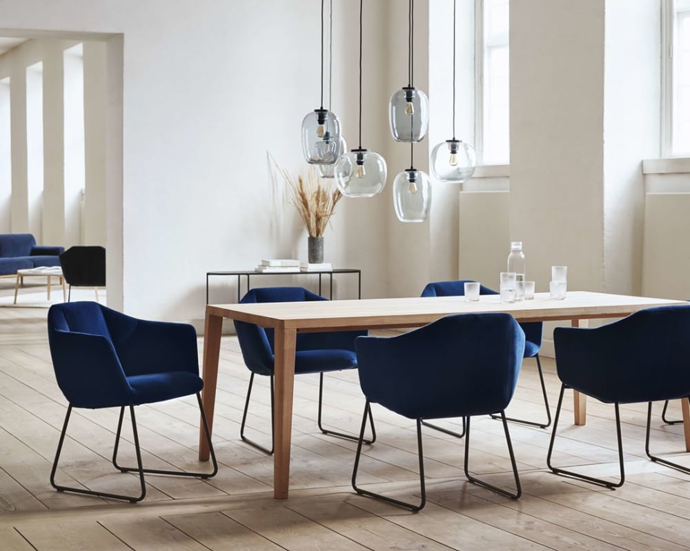 Dining room flooded with natural light, with light wood floors and walls and blue accent dining chairs.<span class="sr-only"> (opened in a new window/tab)</span>