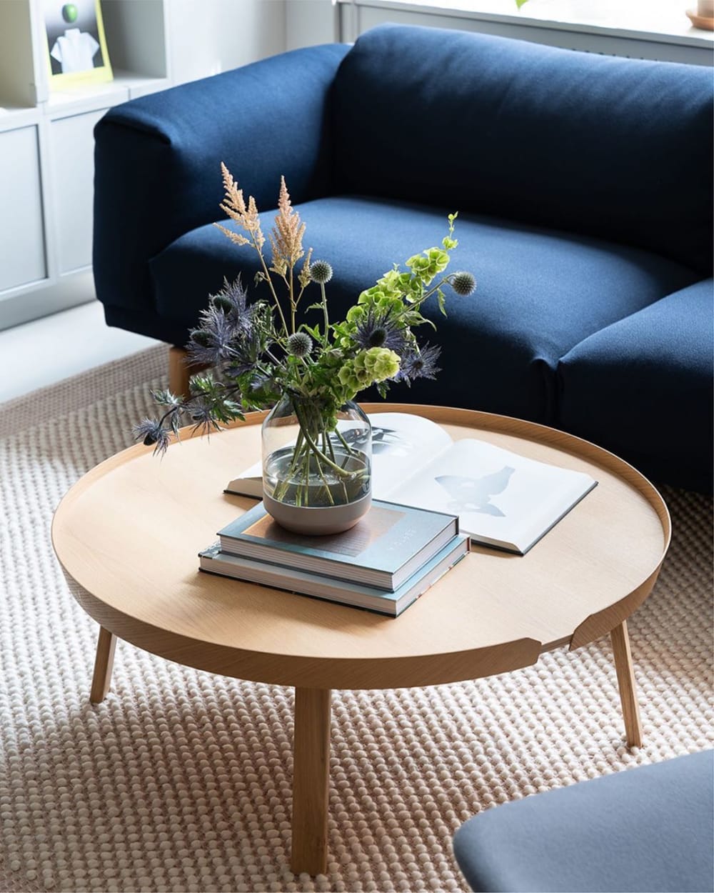 Close-up of a blue sofa and a bunch of flowers over a light wood coffee table.<span class="sr-only"> (opened in a new window/tab)</span>