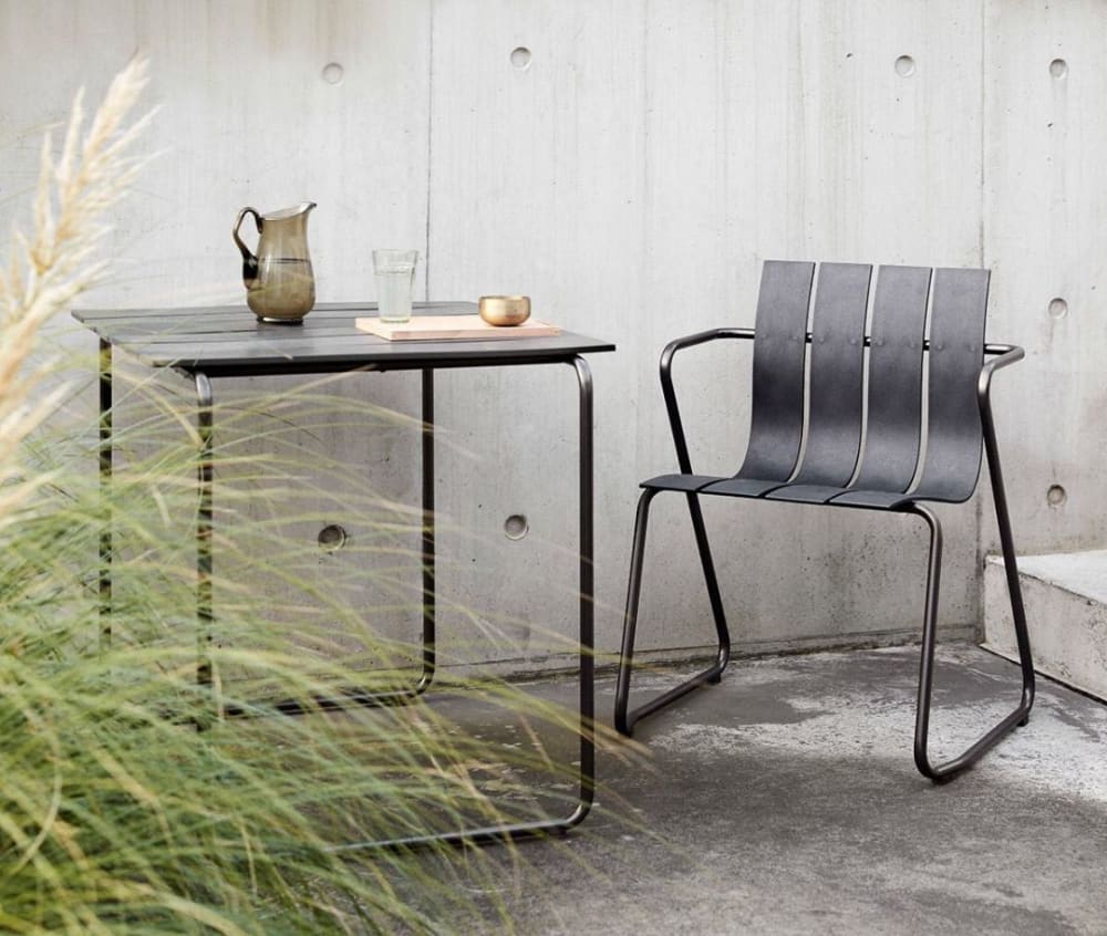 Sustainable plastic chair styled outdoors with a table on the side.<span class="sr-only"> (opened in a new window/tab)</span>