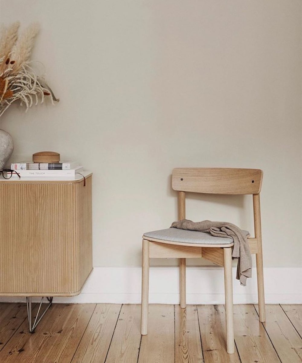 Front view of a sustainable wood chair styled with a blanket on top and a dresser with books and dry flowers on the side.<span class="sr-only"> (opened in a new window/tab)</span>