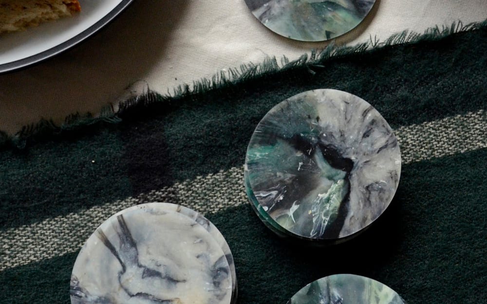 Top view of a table with marbled sustainable coasters made of recycled plastic.<span class="sr-only"> (opened in a new window/tab)</span>