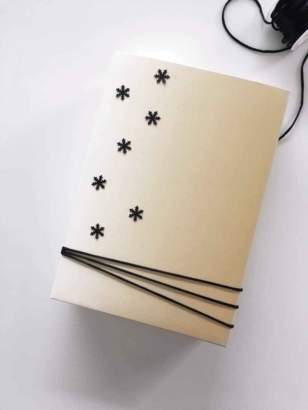 Gift wrapped in a reused box decorated with paper snowflakes as an example of sustainable gift wrapping.<span class="sr-only"> (opened in a new window/tab)</span>