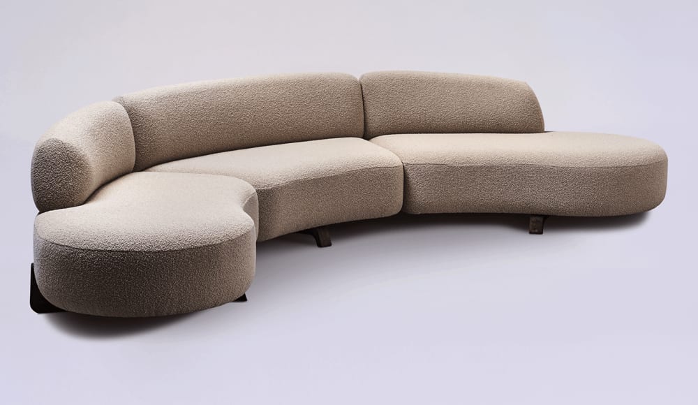 Sofa with a curved profile, beige wool covering and wooden legs.<span class="sr-only"> (opened in a new window/tab)</span>